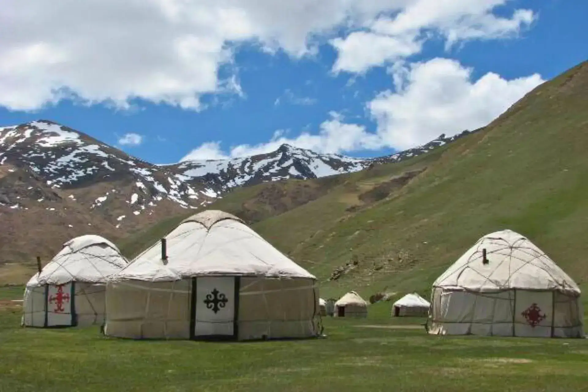 Varias yurtas en el valle de Nurata con las montañas nevadas detrás