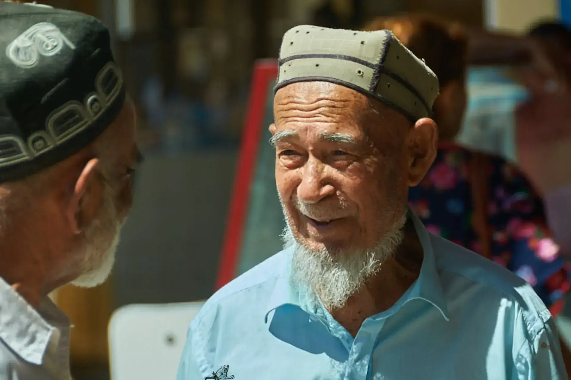 Dos hombres uzbekos con tocado tradicional conversando