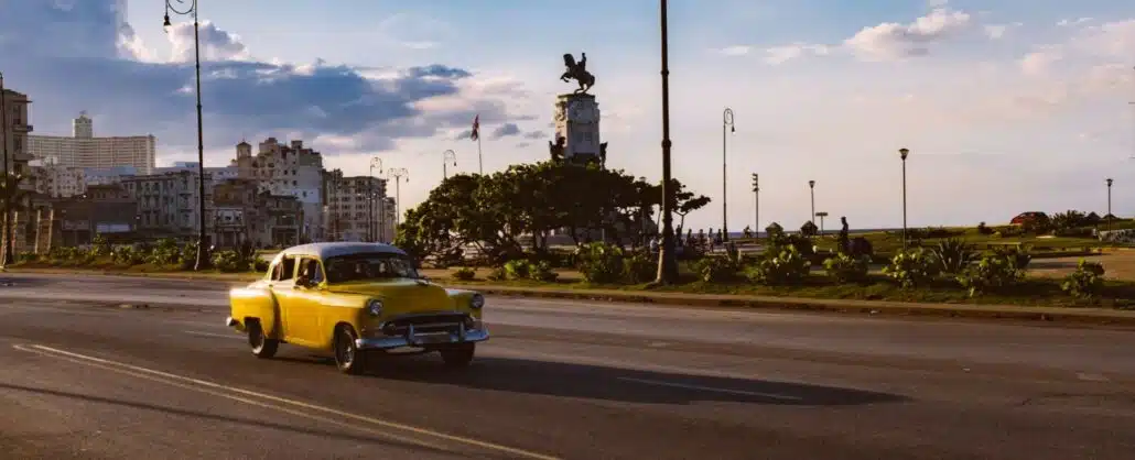 Coche clásico de color amarillo por la carretera en Cuba