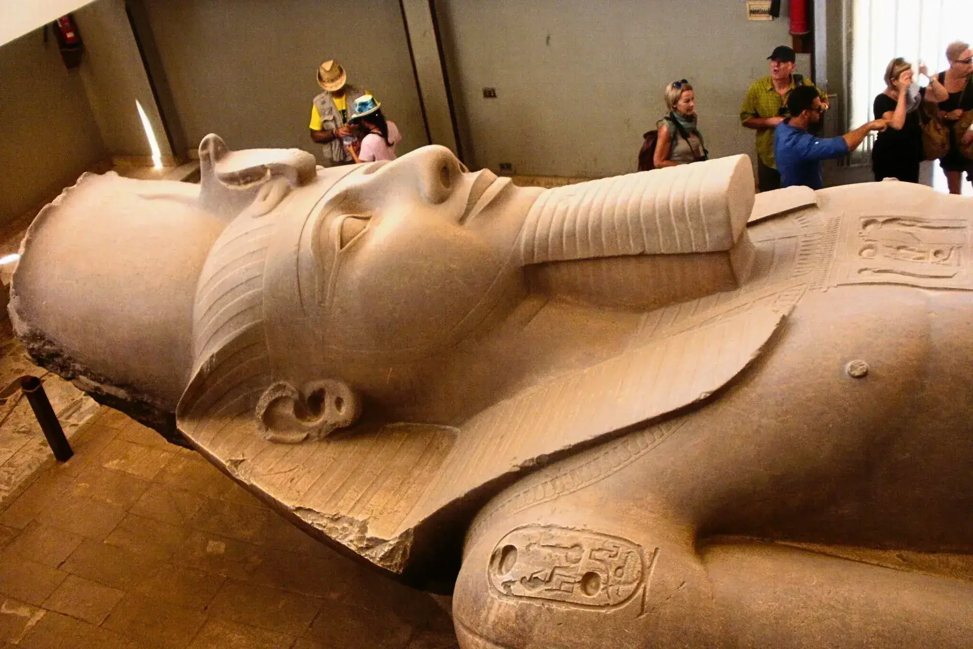 Parte de una estatua gigante de Ramsés ll y viajeros fotografiando alrededor