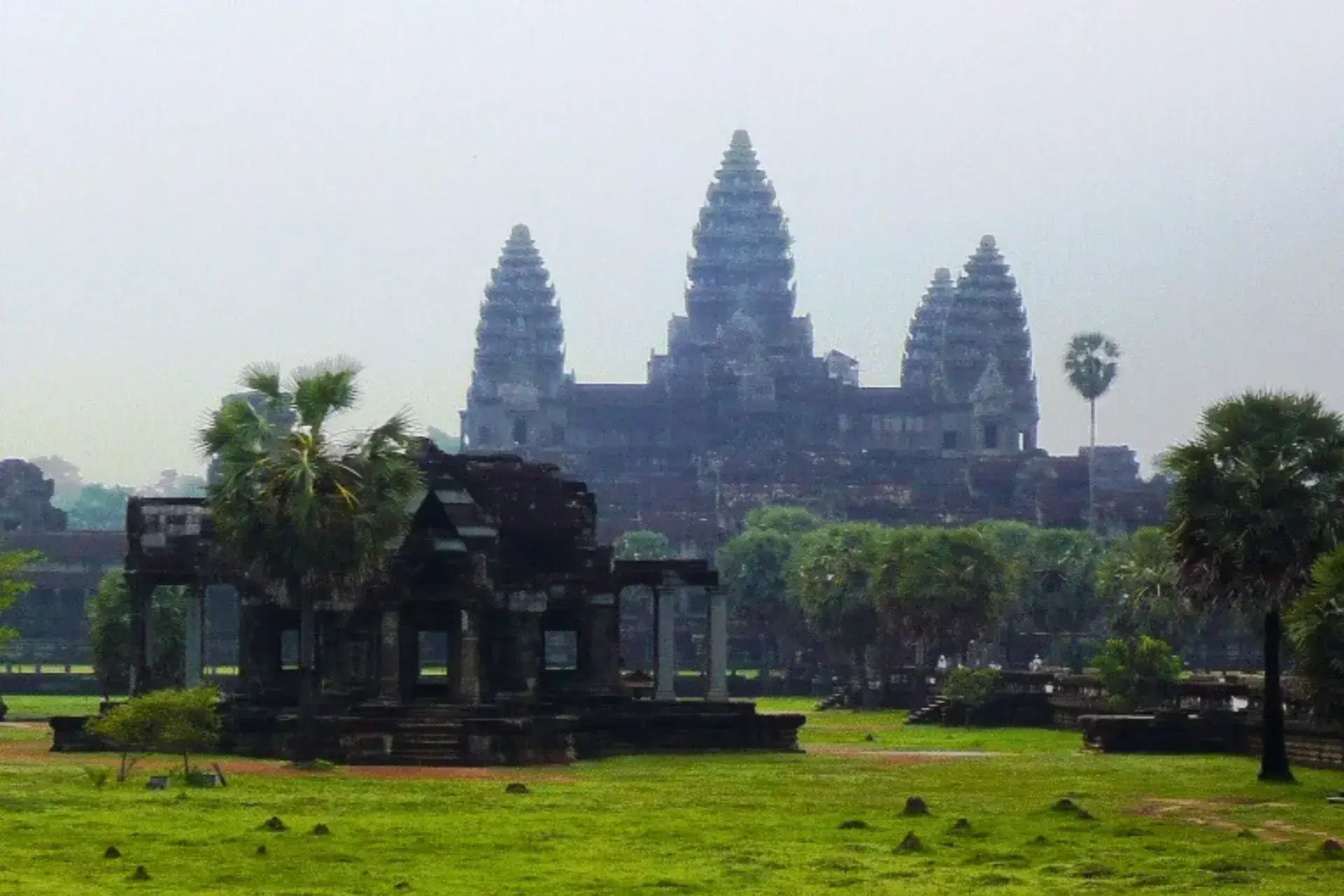 Templo en Angkor Wat con la silueta de dos torres al fondo y vegetación en primer plano
