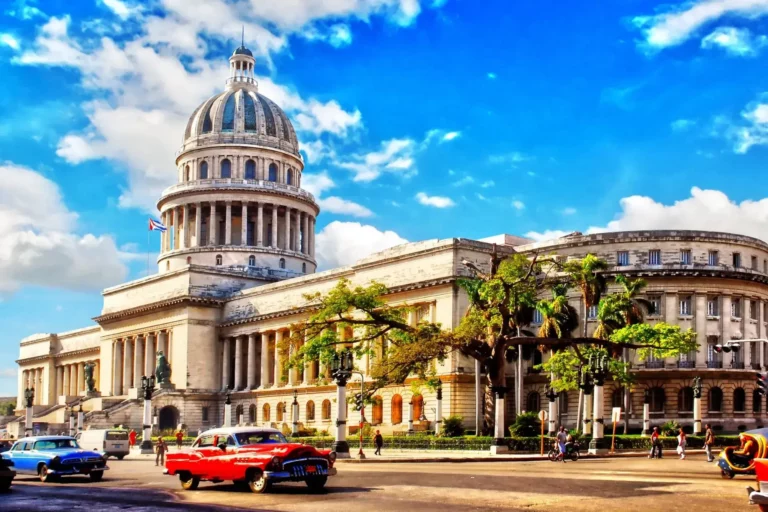 Edificio del capitolio, cielo azul con nubes y coches clásicos transitando