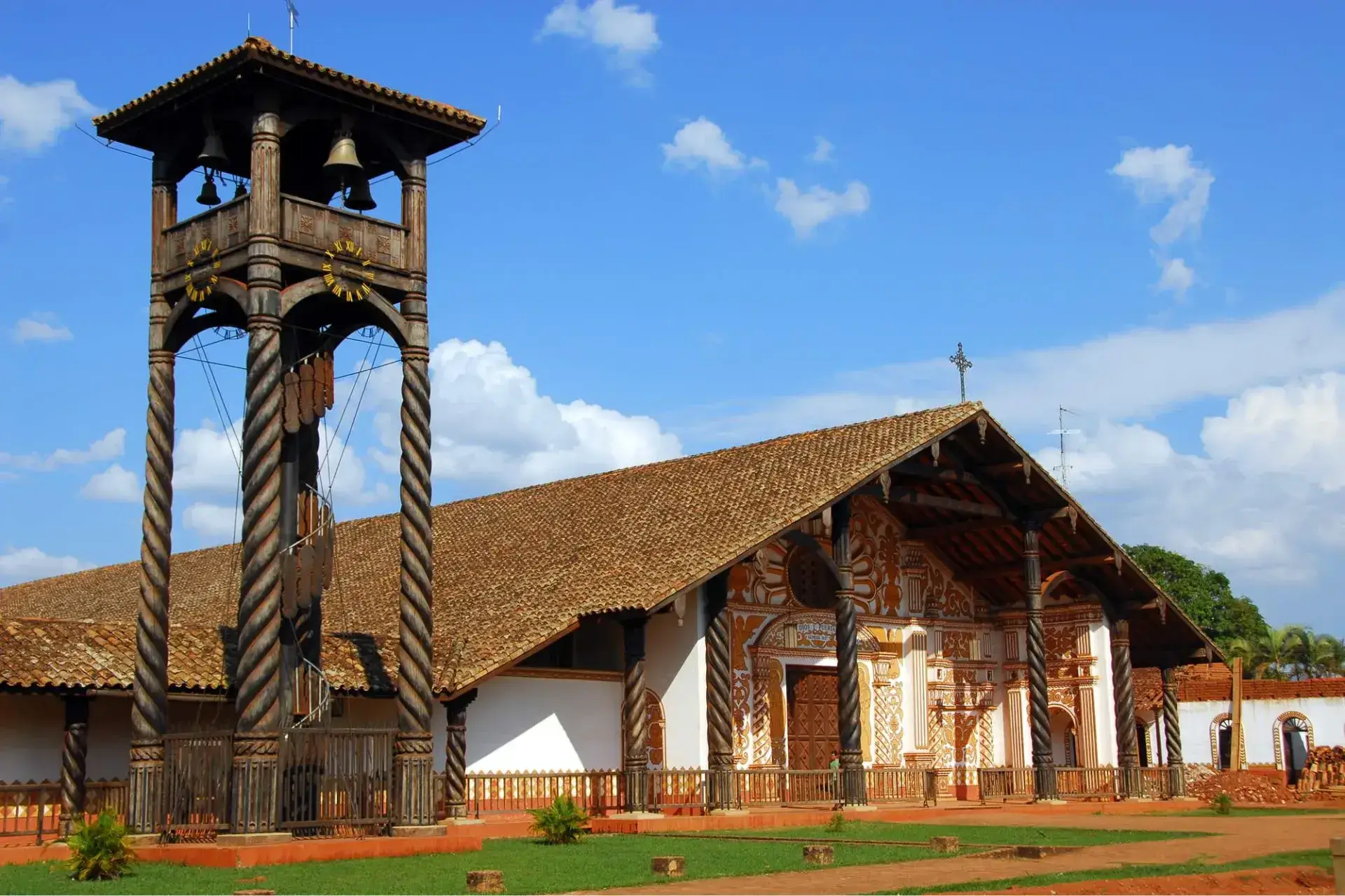 Edificio de una iglesia con tejado a dos aguas, y fachada blanca. Campanario de madera situado a la izquierda