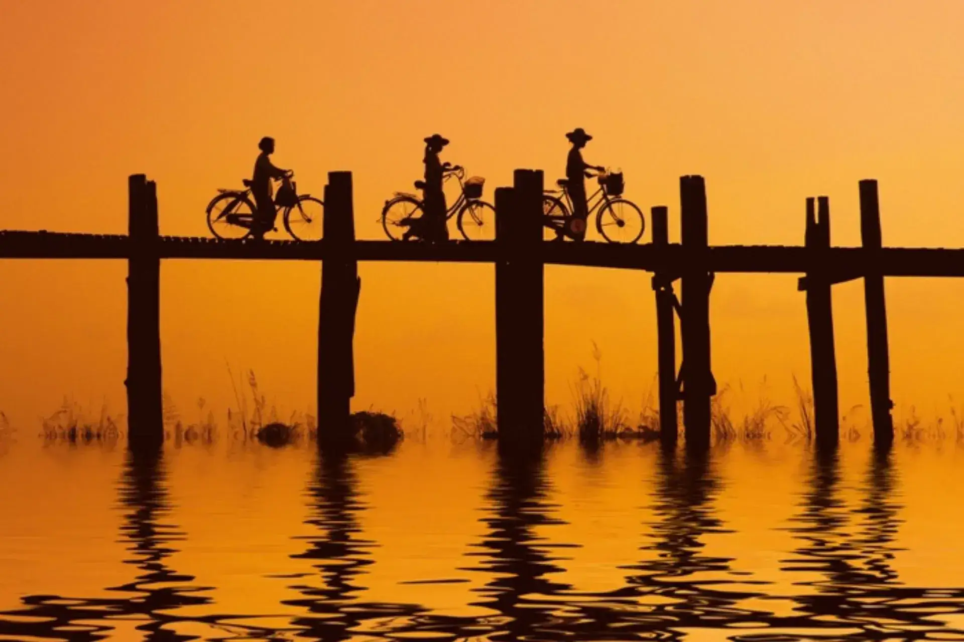 Color anaranjado de un paisaje de agua y la sombra de unos ciclistas al fondo