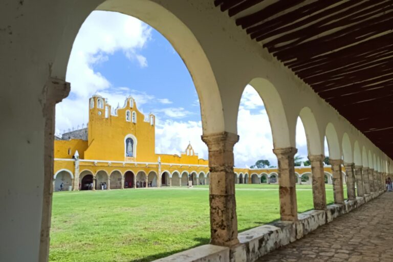 Vistas de una iglesia en una plaza rodeada de arcos y jardines