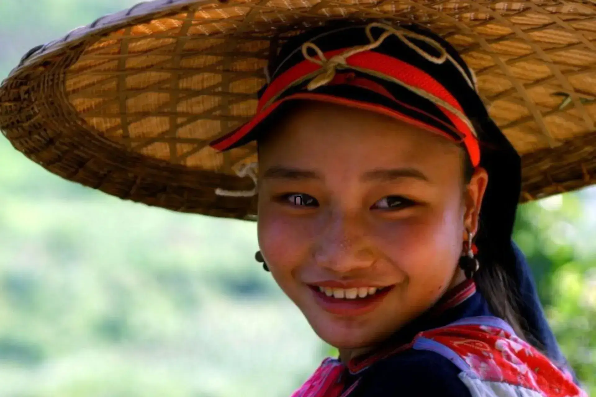 Cara de chica joven asiática sonriendo y portando un gorro tradicional vietnamita