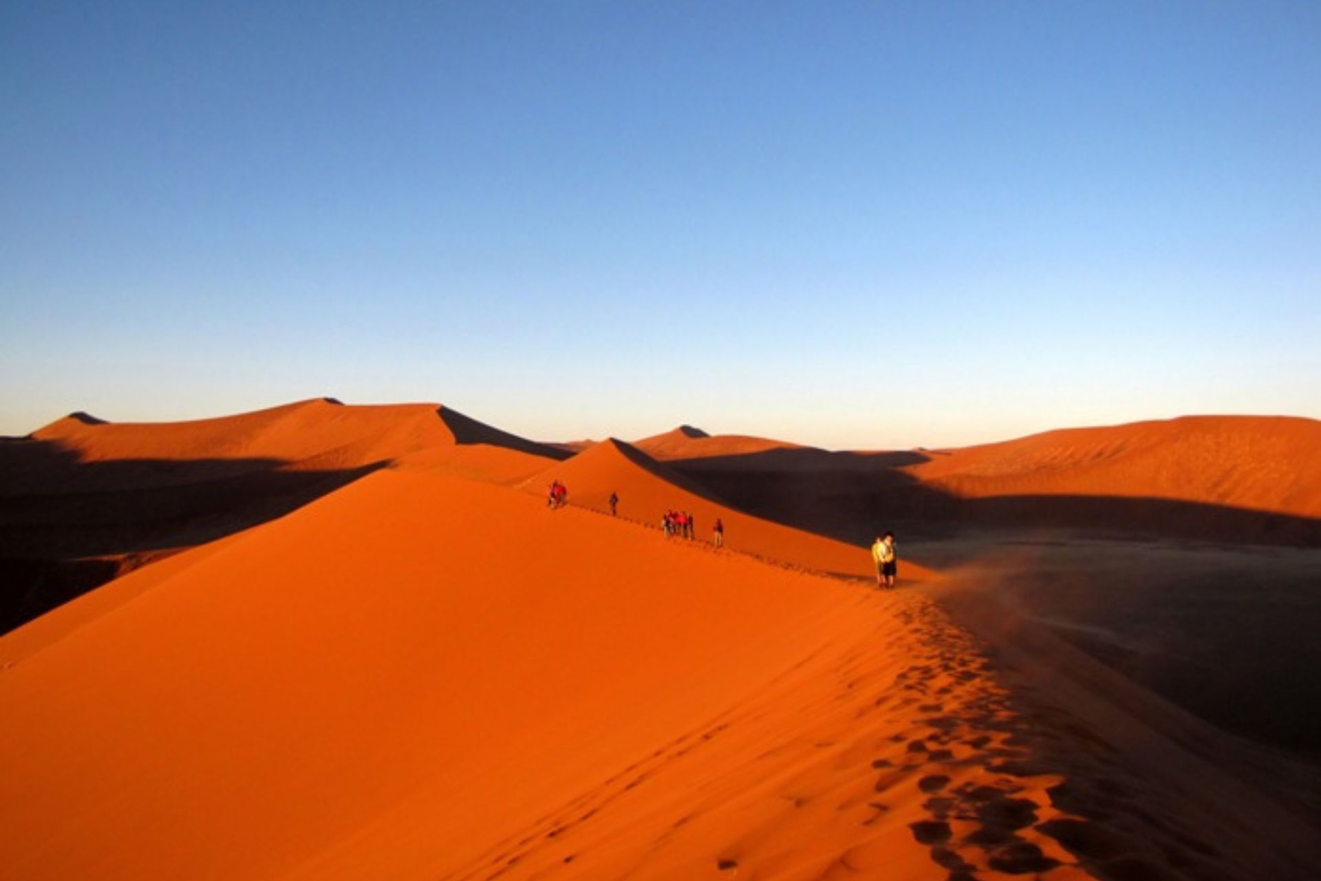 Dunas de arena rojiza con gente andando sobre ellas