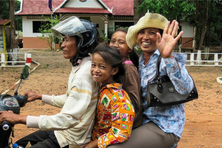 Familia montando una moto, la madre saluda a cámara sonriendo