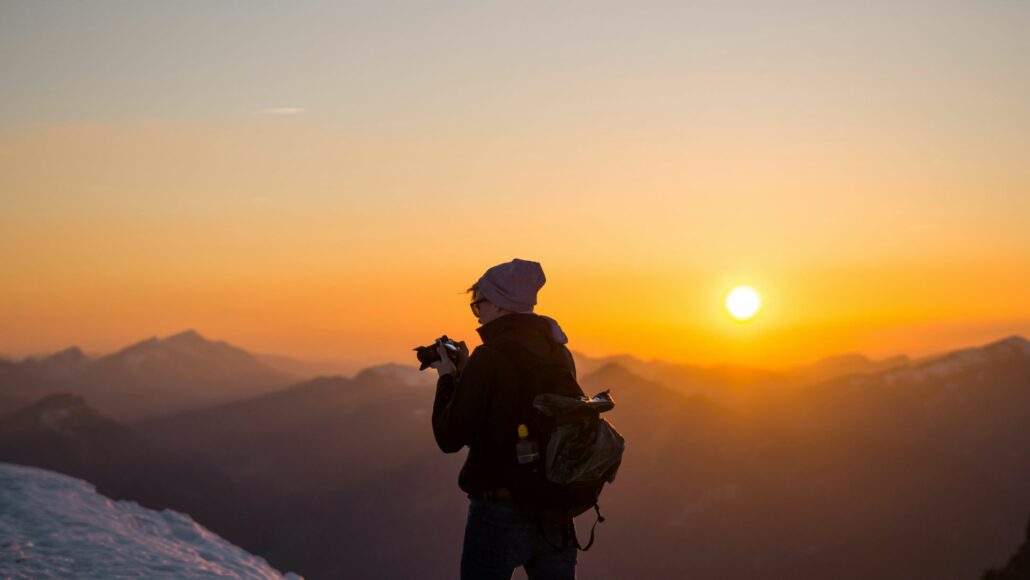 Hombre haciendo fotografías a un atardecer en la montaña
