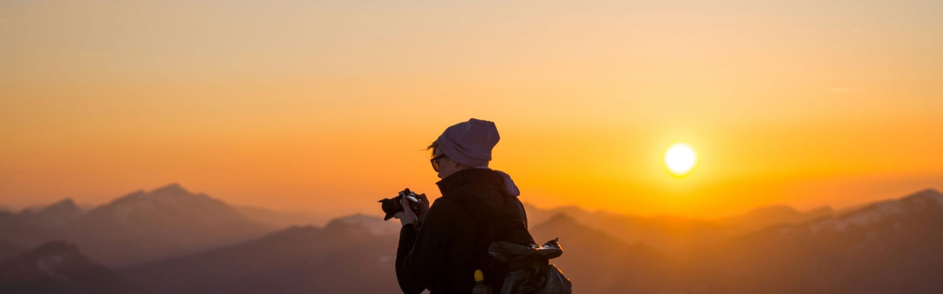 Hombre haciendo fotografías a un atardecer en la montaña