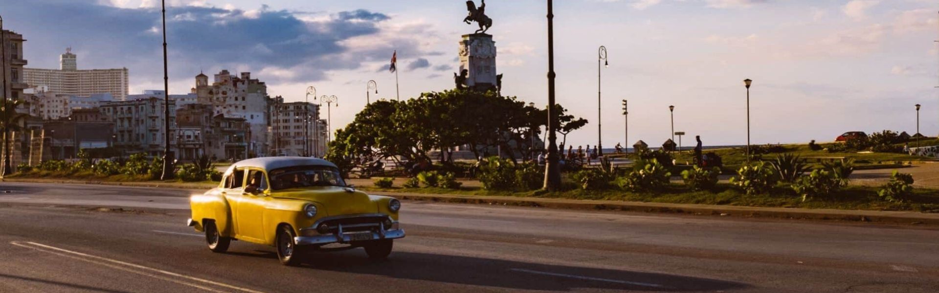 Coche clásico de color amarillo por la carretera en Cuba